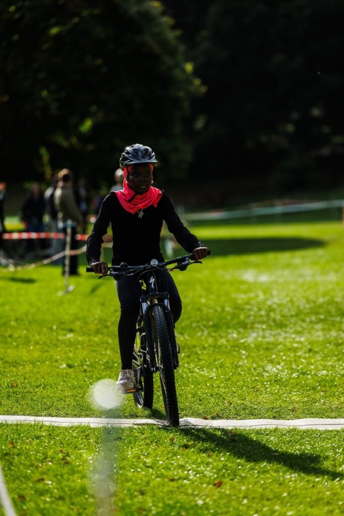 Young rider in a black top and red headscarf racing at the Inch Park Cyclocross
