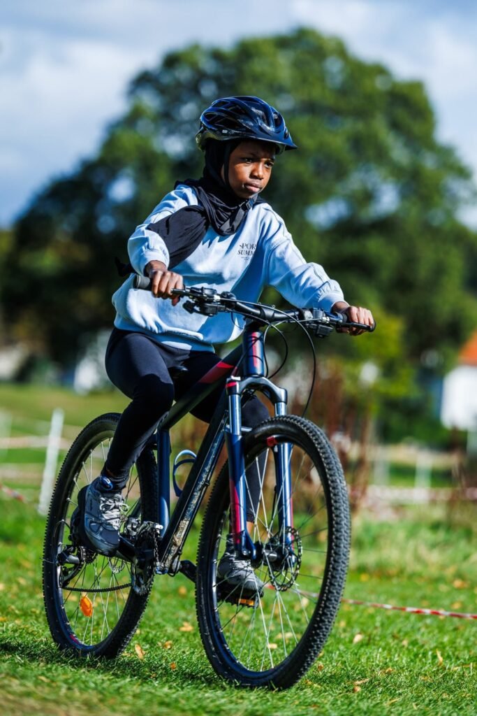 Young rider in a light blue top riding across the grass